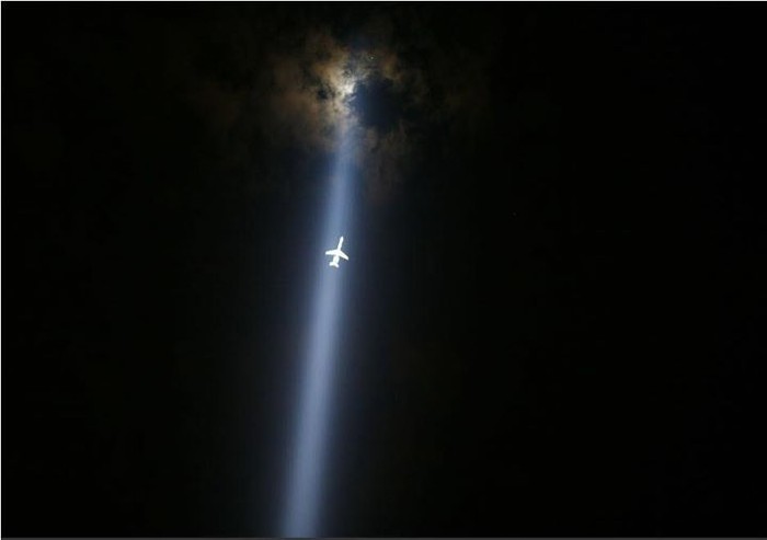 Máy bay di chuyển xuyên qua cột tháp Tribute in Lights được thắp sáng bên cây cầu Brooklyn, vùng Manhattan, thành phố New York nhằm tưởng niệm vụ khủng bố 11/9. Tác giả: Eric Thayer.